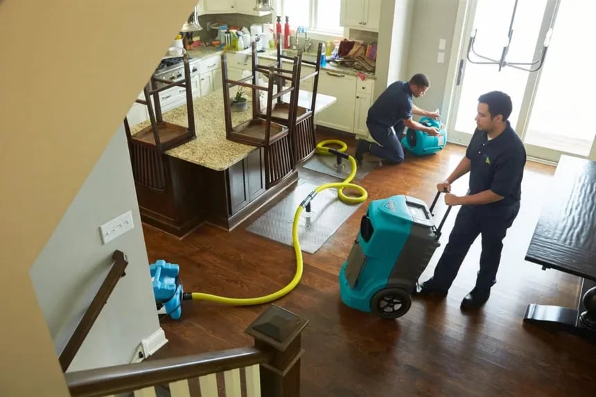 Two technicians performing water damage restoration in a kitchen, overhead view